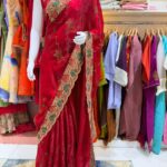 The rich red colour combined with the gold-and-green embroidery gives this saree a luxurious traditional look